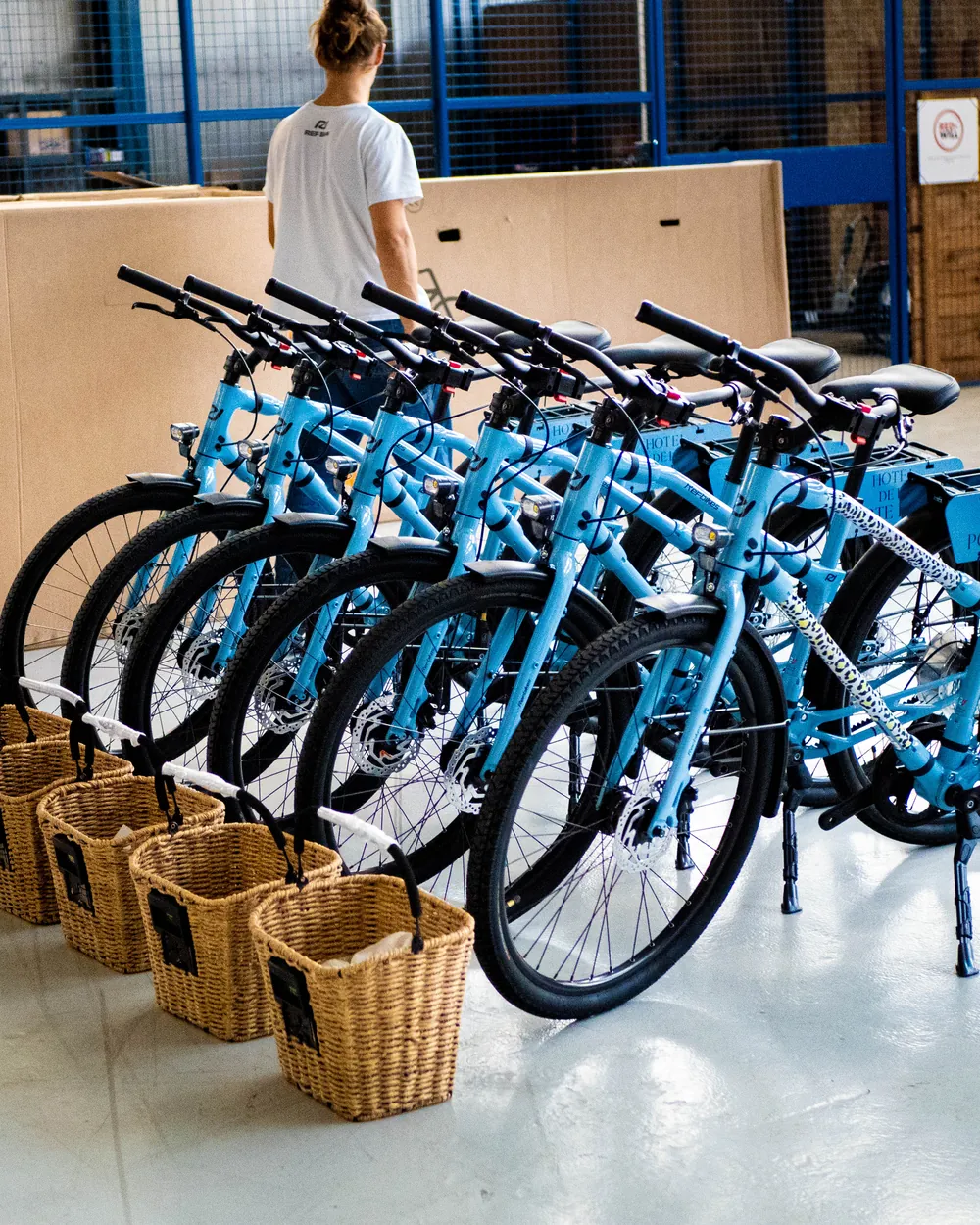 Une flotte de vélos REF Bikes bleus alignés, paniers en osier